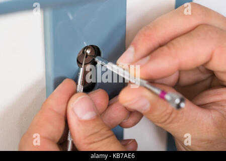 Immagine ritagliata di fissaggio lockpicker maniglia della porta a casa Foto Stock