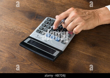 Immagine ritagliata di imprenditore utilizzando la calcolatrice a scrivania in legno Foto Stock