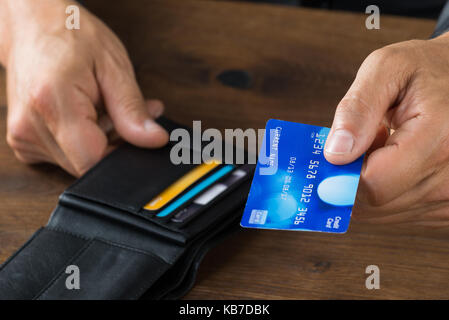 Immagine ritagliata di imprenditore dando carta di credito dal portafoglio a scrivania Foto Stock