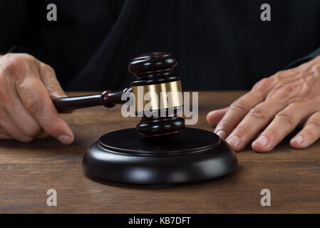 Immagine ritagliata del giudice maschio che colpisce il martello a tavola Foto Stock