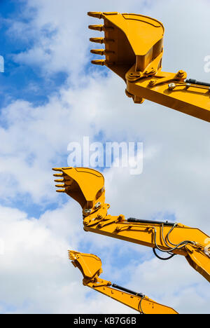 Benne di tre escavatori di scavo contro un cielo blu Foto Stock