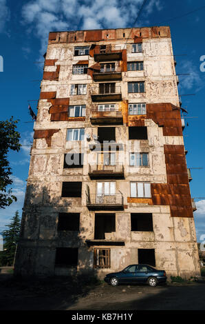 Vecchia auto di fronte abbandonato distrutto il vecchio appartamento residenziale alloggiamento facciata di edificio. finestre rotte coperte da lamiera stagnata. povero quartiere della città di Foto Stock