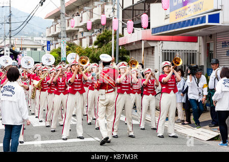 Annualmente Genji parade, Tada, Giappone. Le donne della fascia di vento, indossano tuniche rosa e pantaloni bianchi, in piedi in strada eseguendo. Vista affacciate. Foto Stock