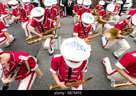 Giappone, Tada, annuale Genji parade. Le donne della banda del vento in rosa tuniche e cappucci bianchi, inginocchiato con strumenti in strada. Il nome di banda sulla parte superiore dei tappi. Foto Stock