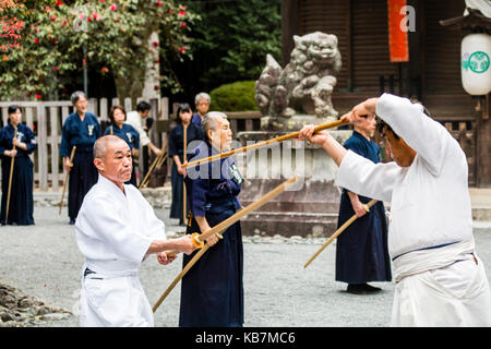 Giapponese uomini vestiti di bianco e gli altri in nero, formazione con  bokken o bokuto, legno spade di samurai, in Tada santuario terreno. Genji  festival Foto stock - Alamy