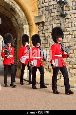 Le truppe della Casa, meglio conosciute come ‘le Guardie’ che marciano attraverso un cancello dal Quadrangle Inside Windsor Castle, Windsor, Berkshire, Inghilterra, Regno Unito Foto Stock
