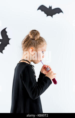 Piccola Ragazza strega in abito nero su accessori magico. halloween, studio di sera. Foto Stock