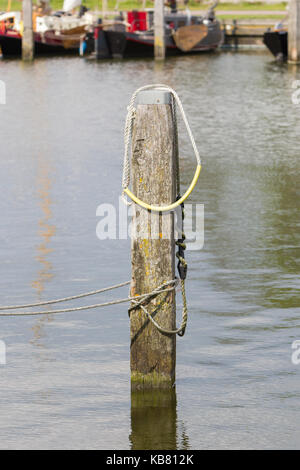 Cima nautica legata intorno a un post sul molo Foto Stock