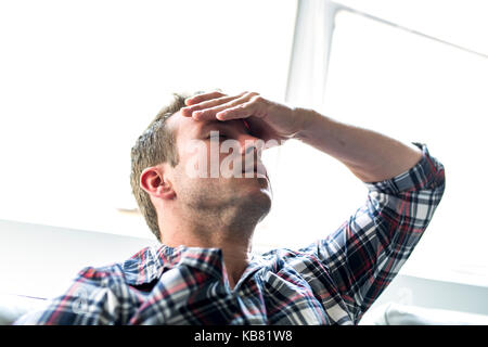 Giovane uomo che soffre di mal di testa a casa Foto Stock