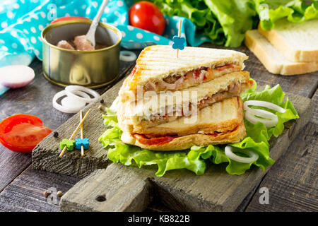 Doppia con sandwich di tonno in scatola e il formaggio feta servite con foglie di lattuga su un tagliere di legno. Foto Stock