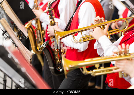 Strumento musicale, brass band e orchestra concetto - closeup ensemble di musicisti di suonare alle trombe e sassofoni in concerto rosso costumi, maschio Foto Stock