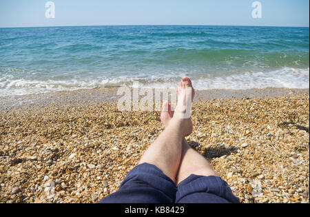 Gli uomini con i piedi sul background del mare spiaggia. Una vacanza in un resort sul mare Foto Stock