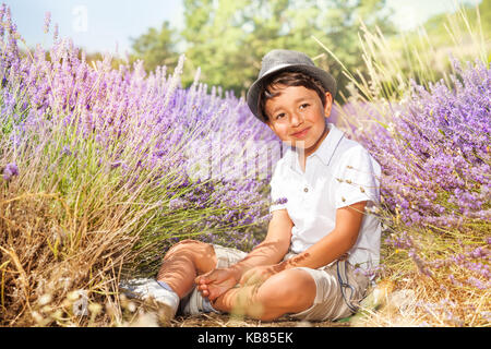 Little Boy indossando hat, seduta in campo di lavanda Foto Stock