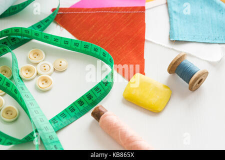 Lavoro di ricamo e cucito Sartoria concetto - close-up sul green metro di misura, pulsanti bianchi, blu e rosa filo in rocchetti e il sapone per il taglio Foto Stock