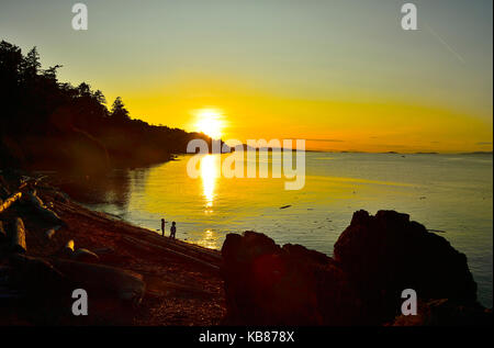 Un paesaggio immagine del tramonto al punto di collo con due ragazzi giocare lungo la spiaggia di Nanaimo sull'Isola di Vancouver British Columbia Canada. Foto Stock