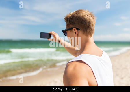 Uomo con lo smartphone a fotografare in estate spiaggia Foto Stock