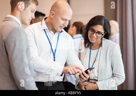 Coppia con smartphone a conferenze di affari Foto Stock