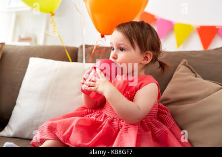 Baby girl bere da sippy cup al compleanno Foto Stock