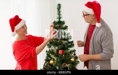 Felice coppia senior decorare albero di natale Foto Stock