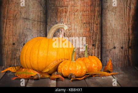 Zucchero zucca torta con due mini zucche, foglie di autunno e ghiande contro di legno rustico sfondo, spazio di copia Foto Stock