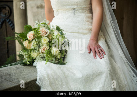 Una candida foto della Sposa tenendo un meraviglioso bouquet. bianco e rosa rose con bimbo di respiro e accenti di colore verde. Foto Stock