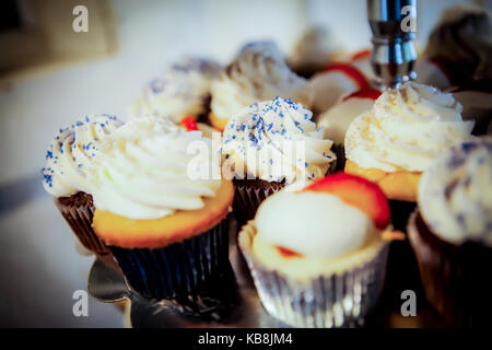 Una varietà di tortine su un piatto di portata con frusta crema, spruzza e fragole. Foto Stock