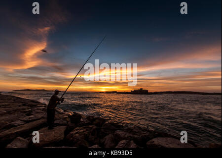 Pescatore cattura i pesci al tramonto Essaouira, Marocco Foto Stock