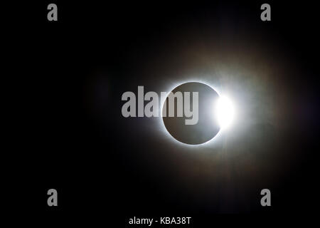 Il sole emerge da dietro la luna in un giorno nuvoloso dopo eclipse Foto Stock
