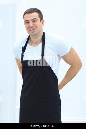 Giovane padre in un grembiule,in piedi in cucina.il concetto di cura. Foto Stock