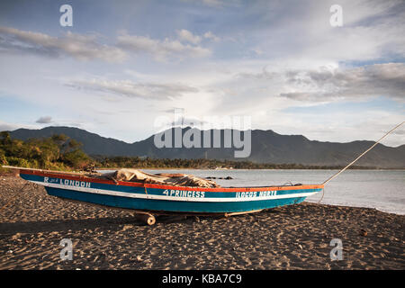 La pesca tradizionale barca ormeggiata sulla spiaggia di saud nelle Filippine durante il tramonto con un meraviglioso sfondo montano. idilliaco paradiso tropicale immagine Foto Stock