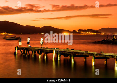 Pescatori su un molo a Ponta das Campanhas, a Armacao Beach, al tramonto. Florianopolis, Santa Catarina, Brasile. Foto Stock