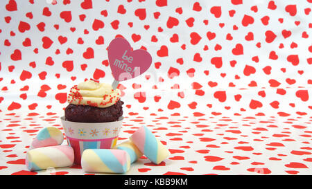 Tortina al cioccolato con crema e a forma di cuore sul segno rosso sfondo cuori Foto Stock