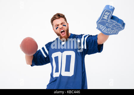 Felice agitato uomo barbuto con faccia dipinta mantenendo la ventola giocattoli e guardando la telecamera isolato su bianco Foto Stock