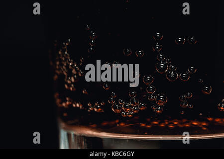 Close-up di vetro rinfrescante di cola bevanda frizzante con bolle di dettagliate su sfondo scuro Foto Stock