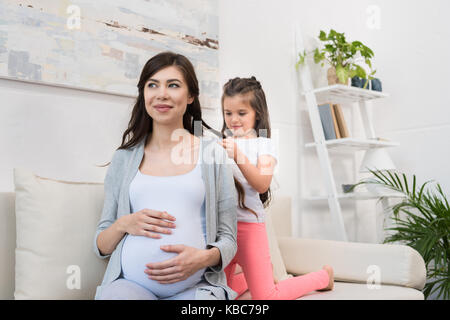 Bambina un intreccio di capelli della madre durante la gravidanza Foto Stock