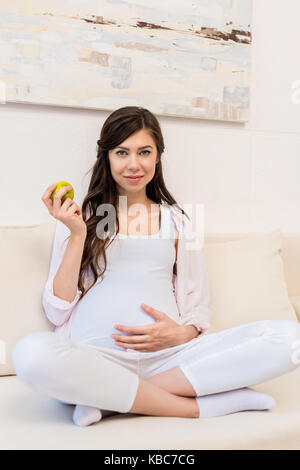 Donna incinta azienda apple Foto Stock