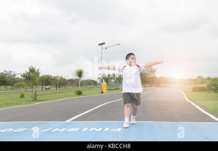 Felice asian Fat Boy in esecuzione per la riga finita., esercizio e un sano concetto Foto Stock