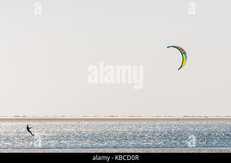 La silhouette di un kite surfer sulla laguna a Walvis Bay nel deserto del Namib sulla costa atlantica della Namibia Foto Stock
