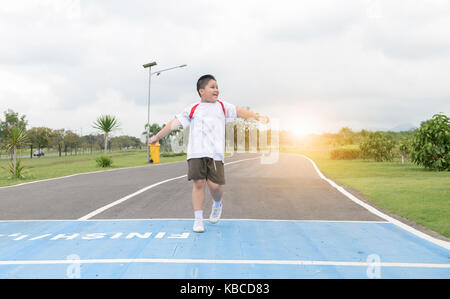 Felice asian Fat Boy in esecuzione per la riga finita., esercizio e un sano concetto Foto Stock