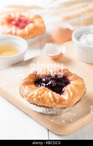 Pane danese con mirtillo e marmellata su topping bianco su uno sfondo di legno, prodotti alimentari da forno Foto Stock