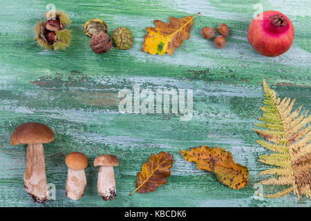 Autunno decorativo confine con castagne, noci, nocciole, acorn,spomegranate e foglie verdi su sfondo di legno Foto Stock