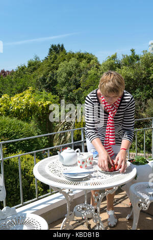 Donna foto-stylist prepara un set su un interesse domestici magazine photo shoot in devon in una giornata di sole. Foto Stock