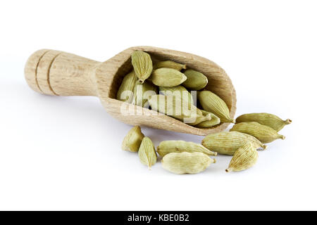 Materie verde biologico i semi di cardamomo in cucchiaio di legno isolato su sfondo bianco Foto Stock