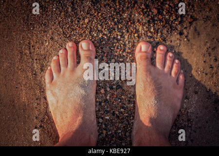 Close up di un piede di un uomo in piedi sulla spiaggia in estate Foto Stock