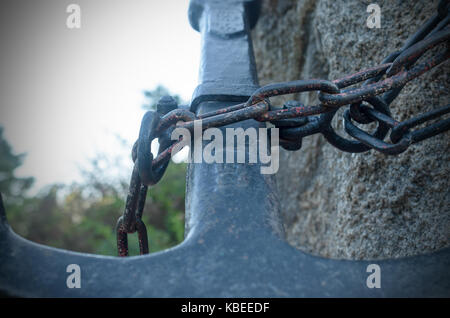 Una statua di un ampio ancoraggio metallico, incatenato ad una pietra Foto Stock