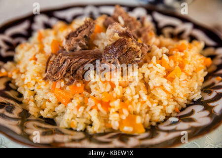 Uzbek pilaf, un piatto tradizionale del centro di cucina asiatica, su una piastra con pattern orientali Foto Stock