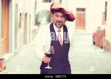 Coppia uomo felice con un bicchiere di vino rosso all'aperto nel vecchio villaggio italiano Foto Stock