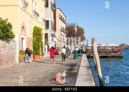 Zattere, Dorsoduro, Venezia, Veneto, Italia in tarda serata luce con i turisti camminare e mangiare in un ristorante a cielo aperto su un pontone Foto Stock