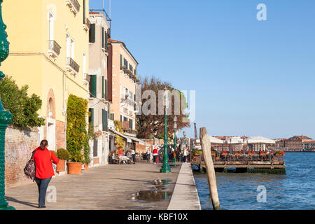 Zattere, Dorsoduro, Venezia, Veneto, Italia al tramonto con i turisti di mangiare in ristoranti all'aperto sulla fondamenta e su un pontone nella Giudecca Foto Stock