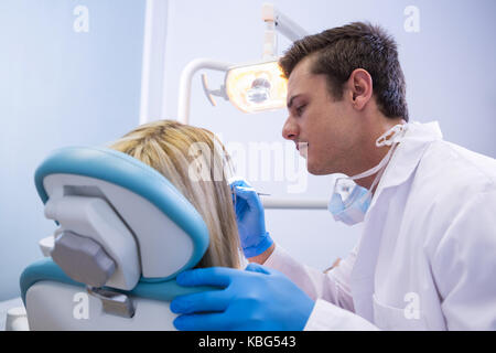 Vista laterale del dentista donna di lucidatura dei denti clinica dentale Foto Stock